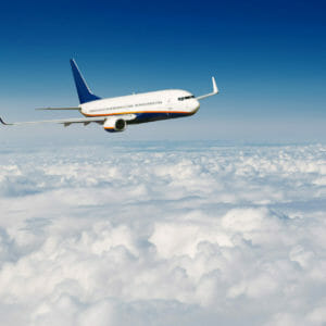 Commercial airplane flying above clouds on blue sky background