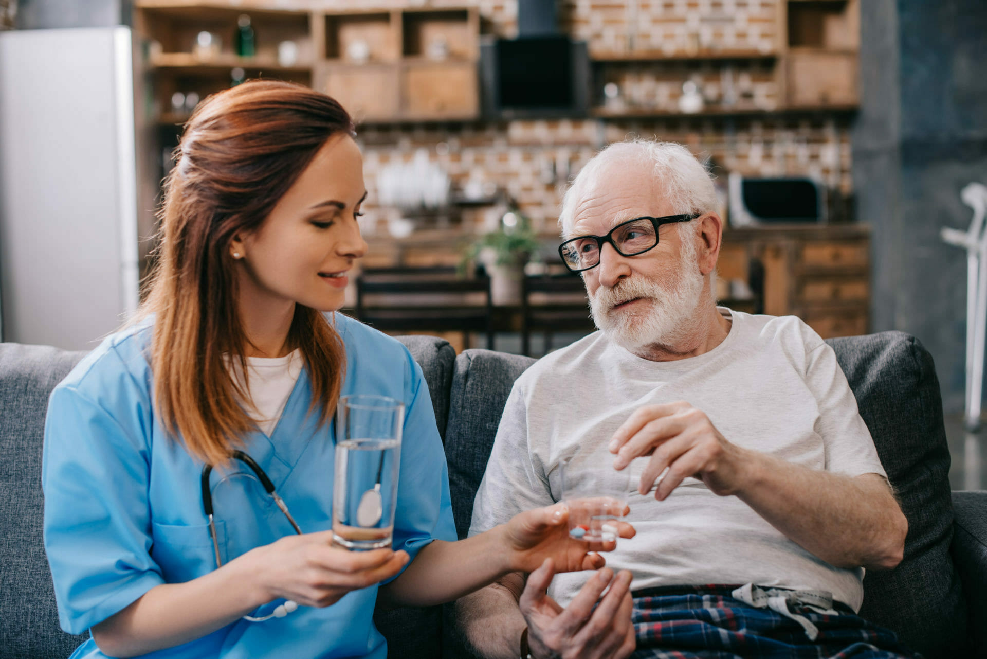 Krankenschwester gibt dem Patienten mit Pillen ein Glas Wasser